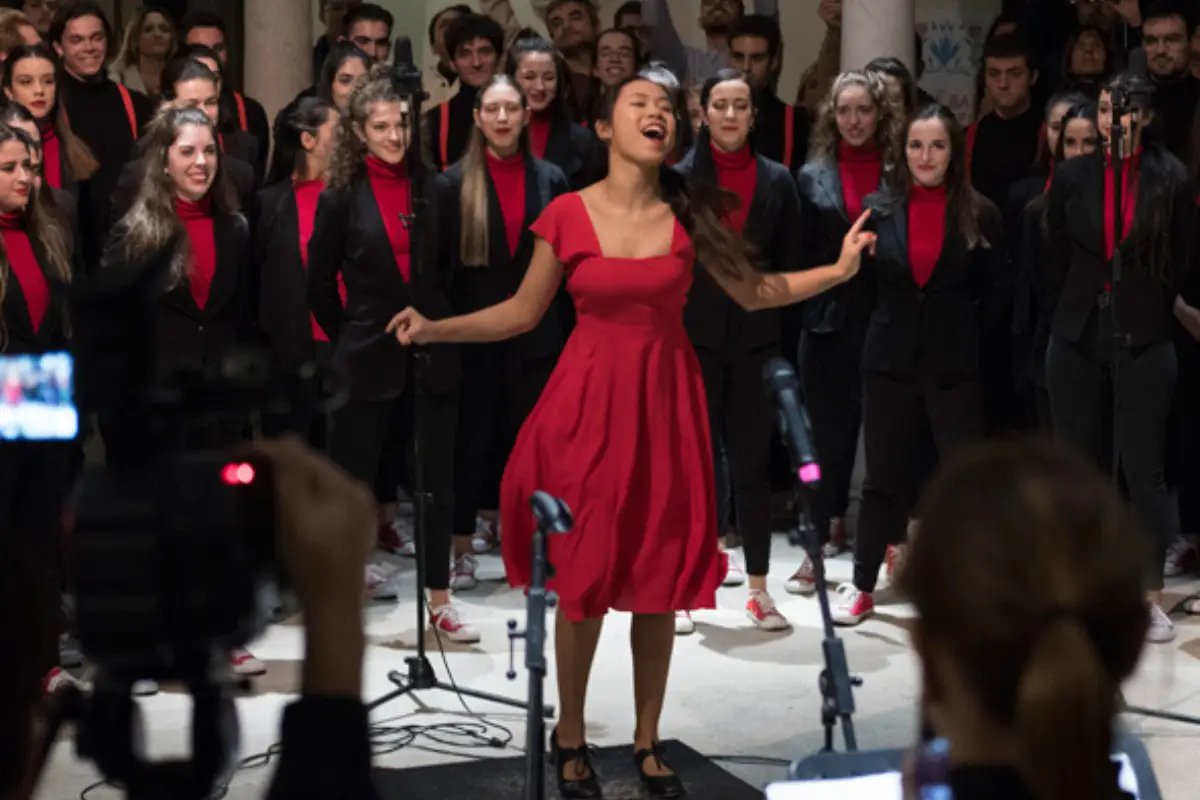 A woman in a red dress singing with many backup singers behind her at the Carmen Thyssen museum in Malaga.
