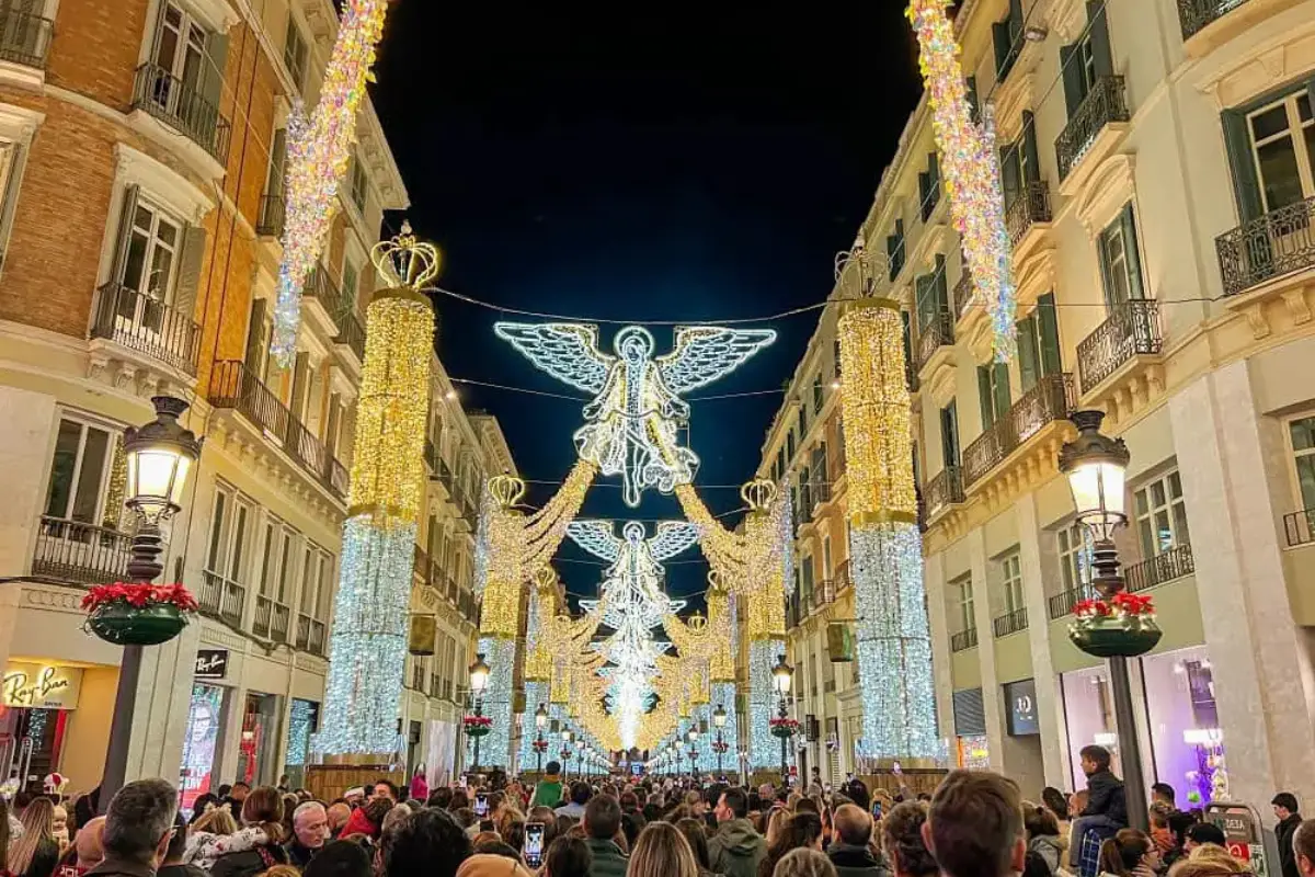 Golden Christmas lights depicting angels stretching down Calle Larios, seen from the end of the street.