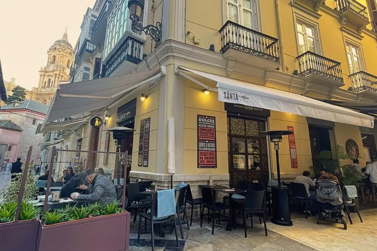 Tables and chairs lining the outside of a yellow building.