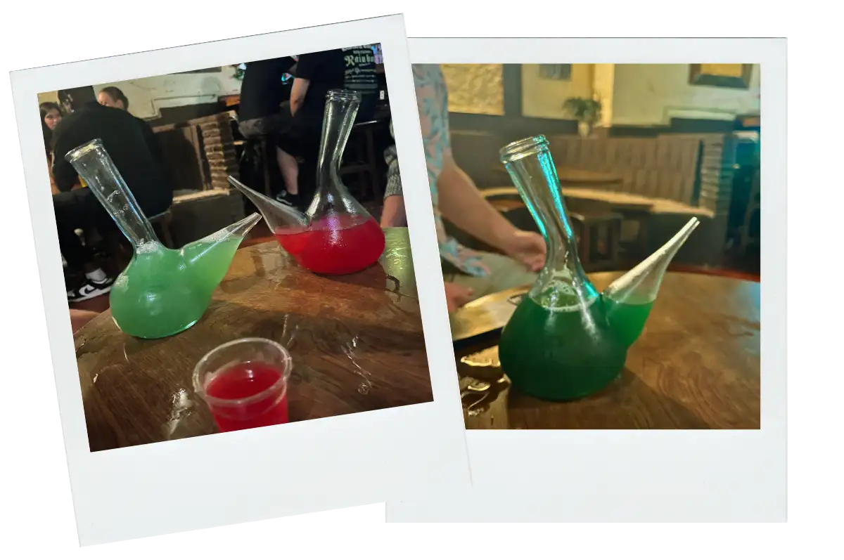 A table with Porrones filled with green and red alcohol.