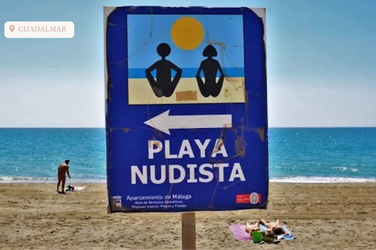 The playa nudista sign at playa guadalmar with sand and ocean behind it.