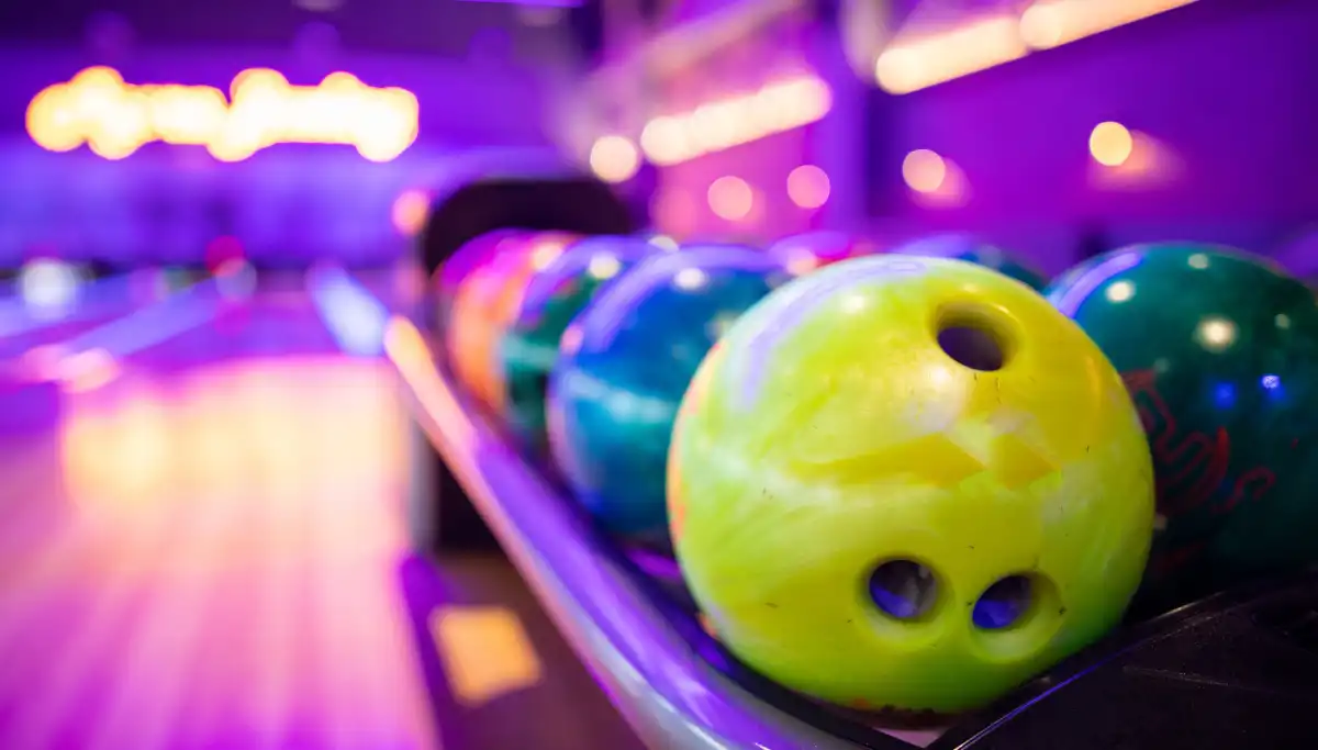 Colourful bowling balls under neon lights at a Malaga bowling alley