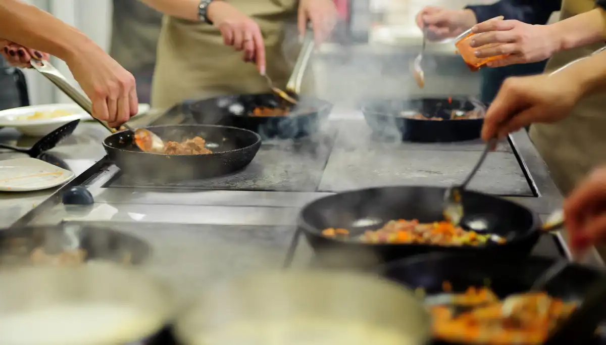 Participants stirring pans during a hands-on Spanish cooking class in Malaga