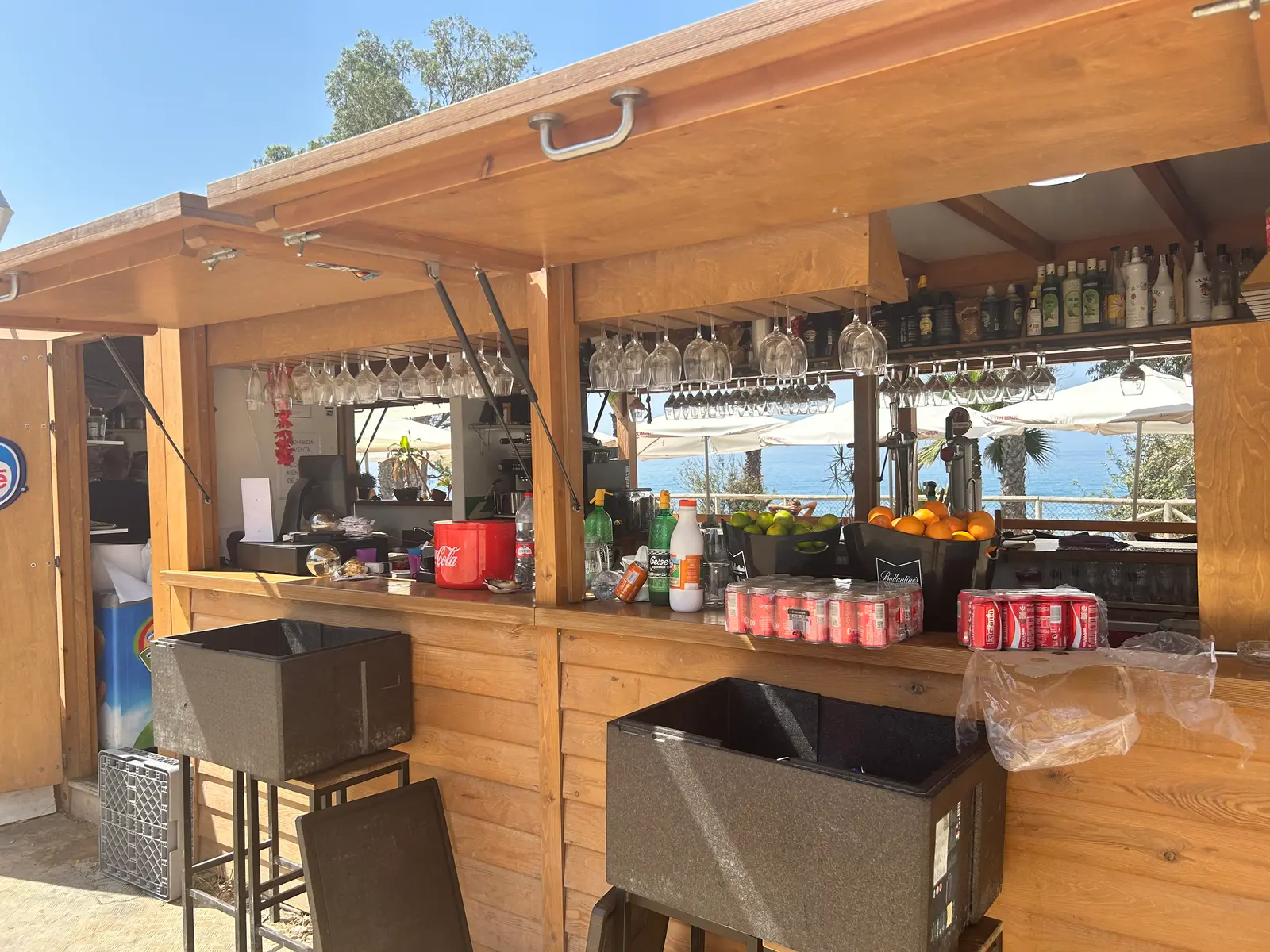 The bar counter at El Cuervo, stocked with drinks and fresh fruit, sea view behind
