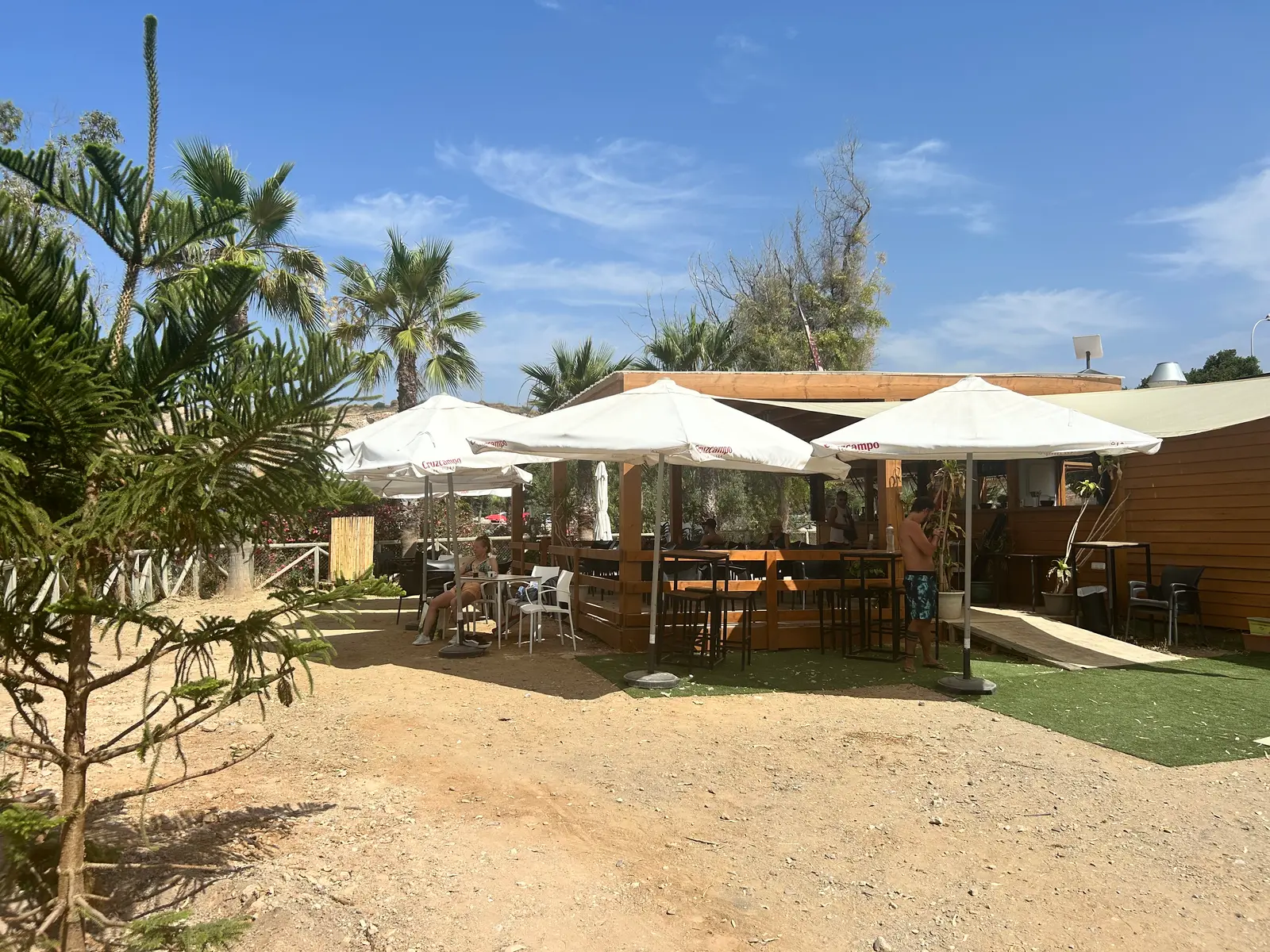 El Cuervo beach bar terrace with parasols and palms at Peñón del Cuervo