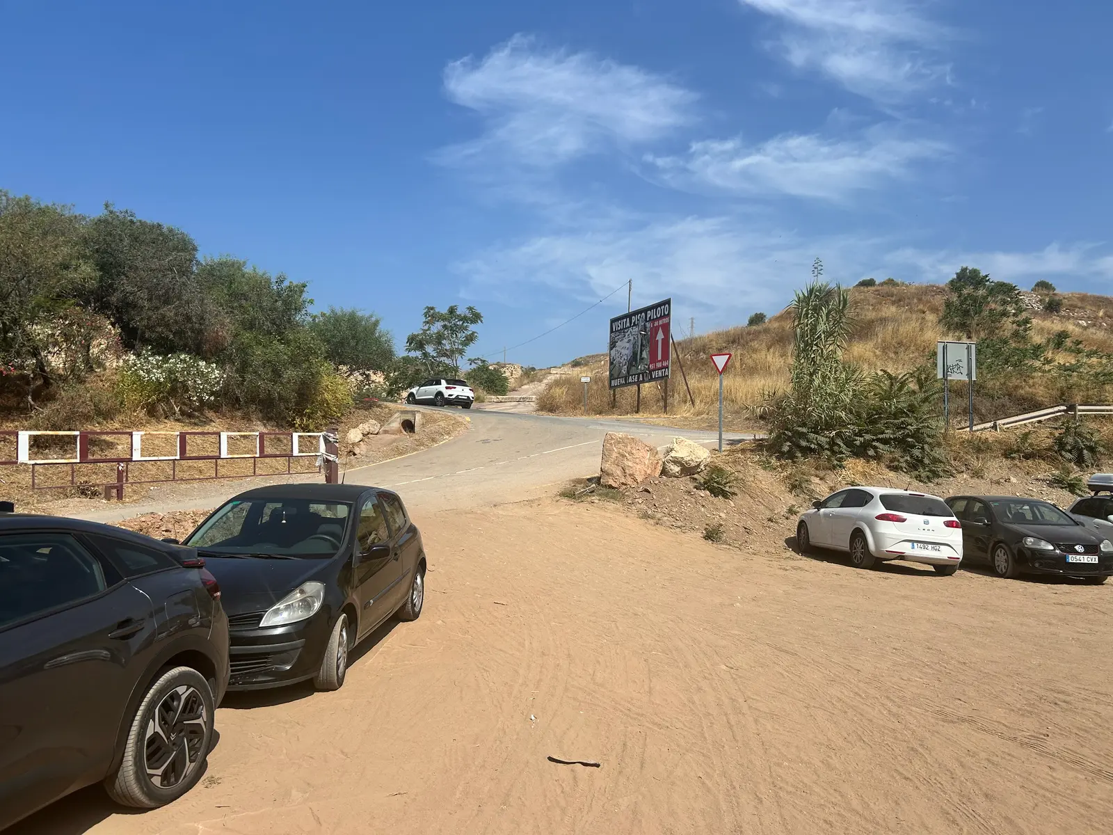 The access road down to Playa Peñón del Cuervo, with cars parked along the dirt verge