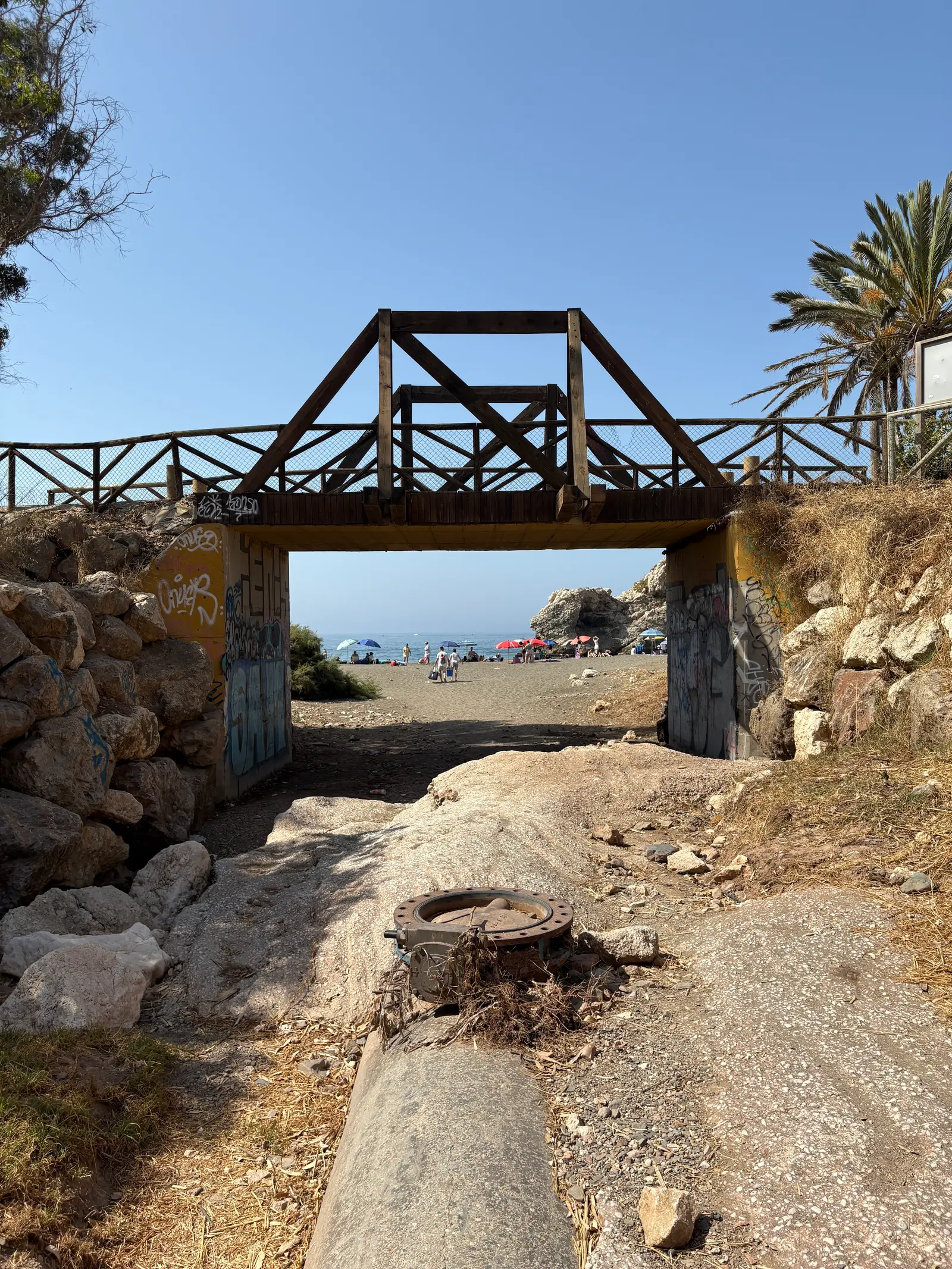 Beachgoers and umbrellas crowded onto the sand at Playa Peñón del Cuervo, seen through the tunnel entrance
