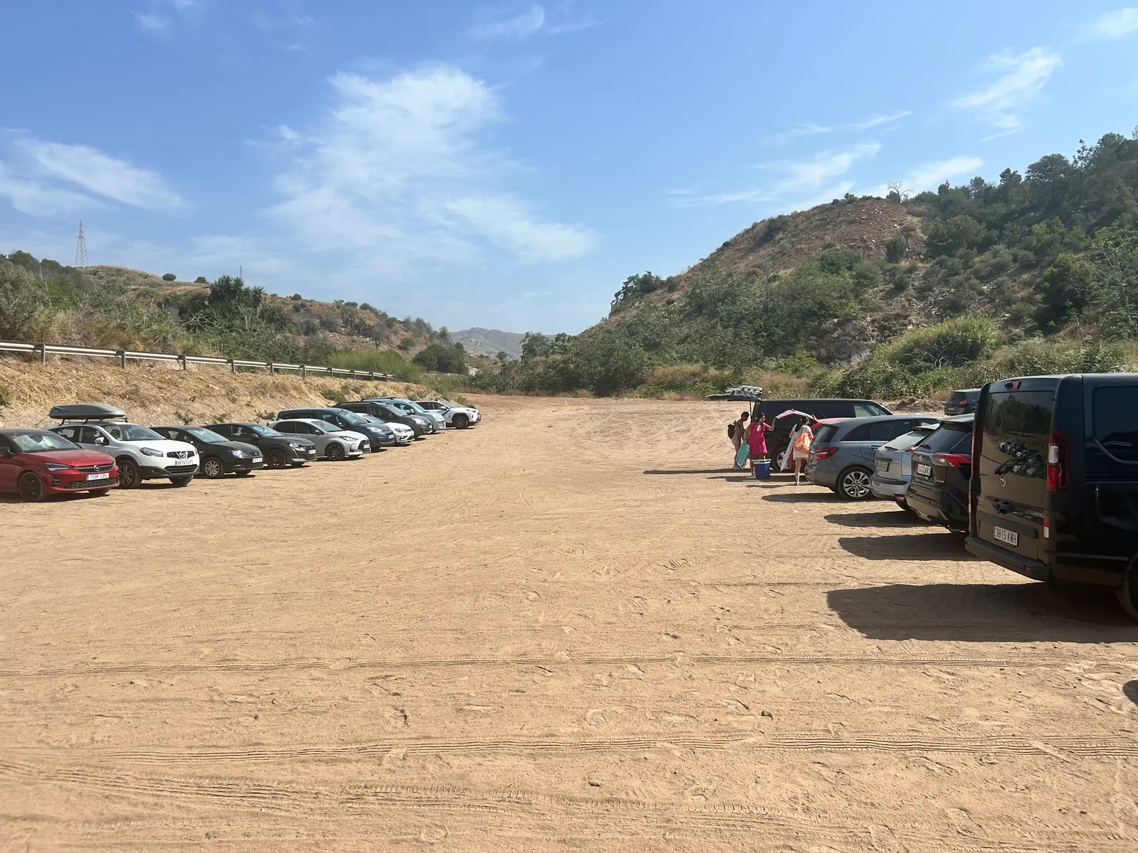 The dirt parking area at Playa Peñón del Cuervo, already filling up with cars