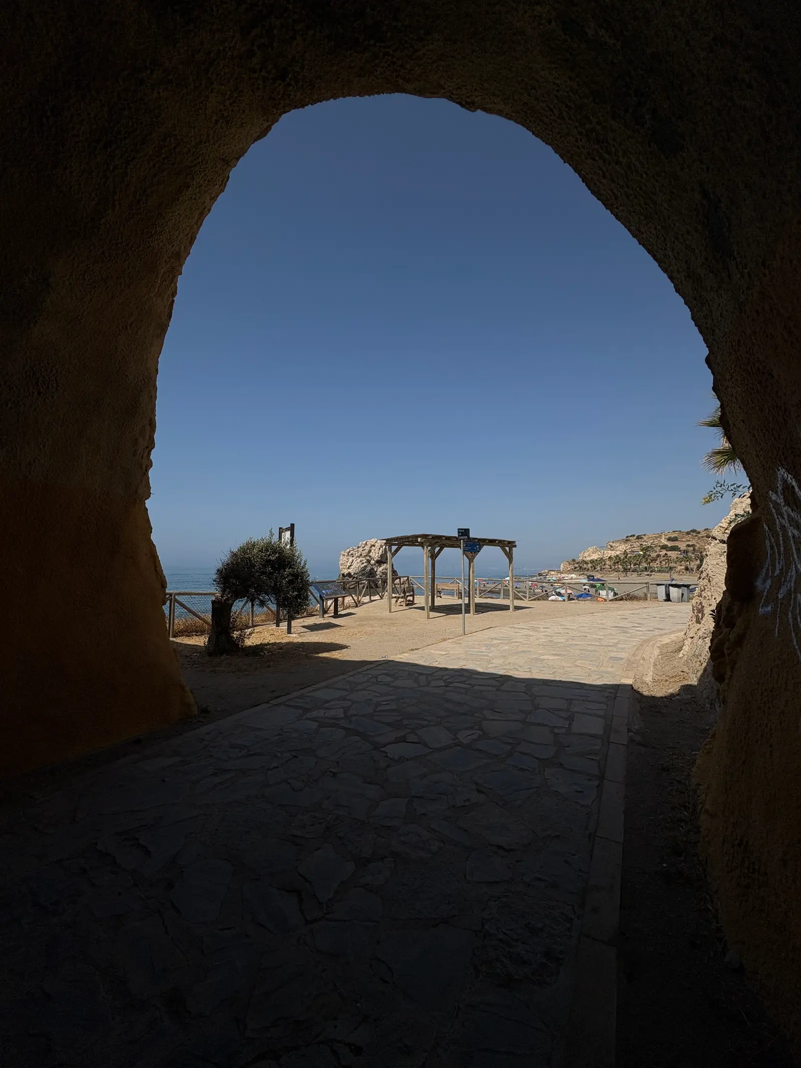 Looking out through a rock tunnel to Playa Peñón del Cuervo and its lifeguard tower