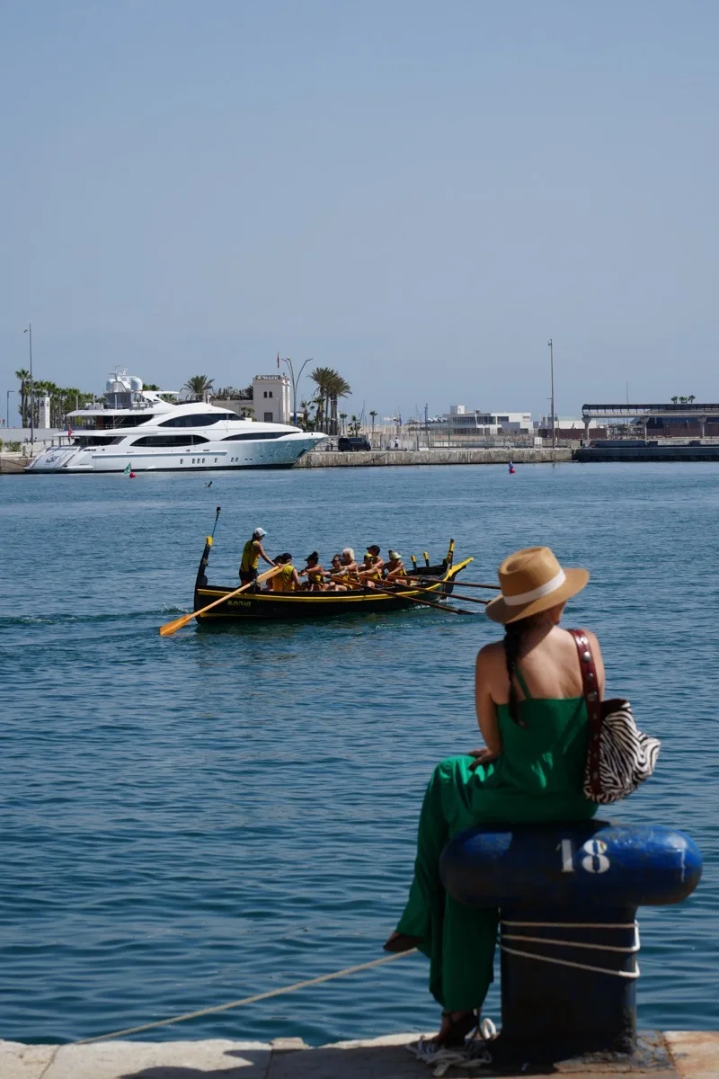 Heidi in a green dress watching a jábega rowing race from the harbour in Málaga