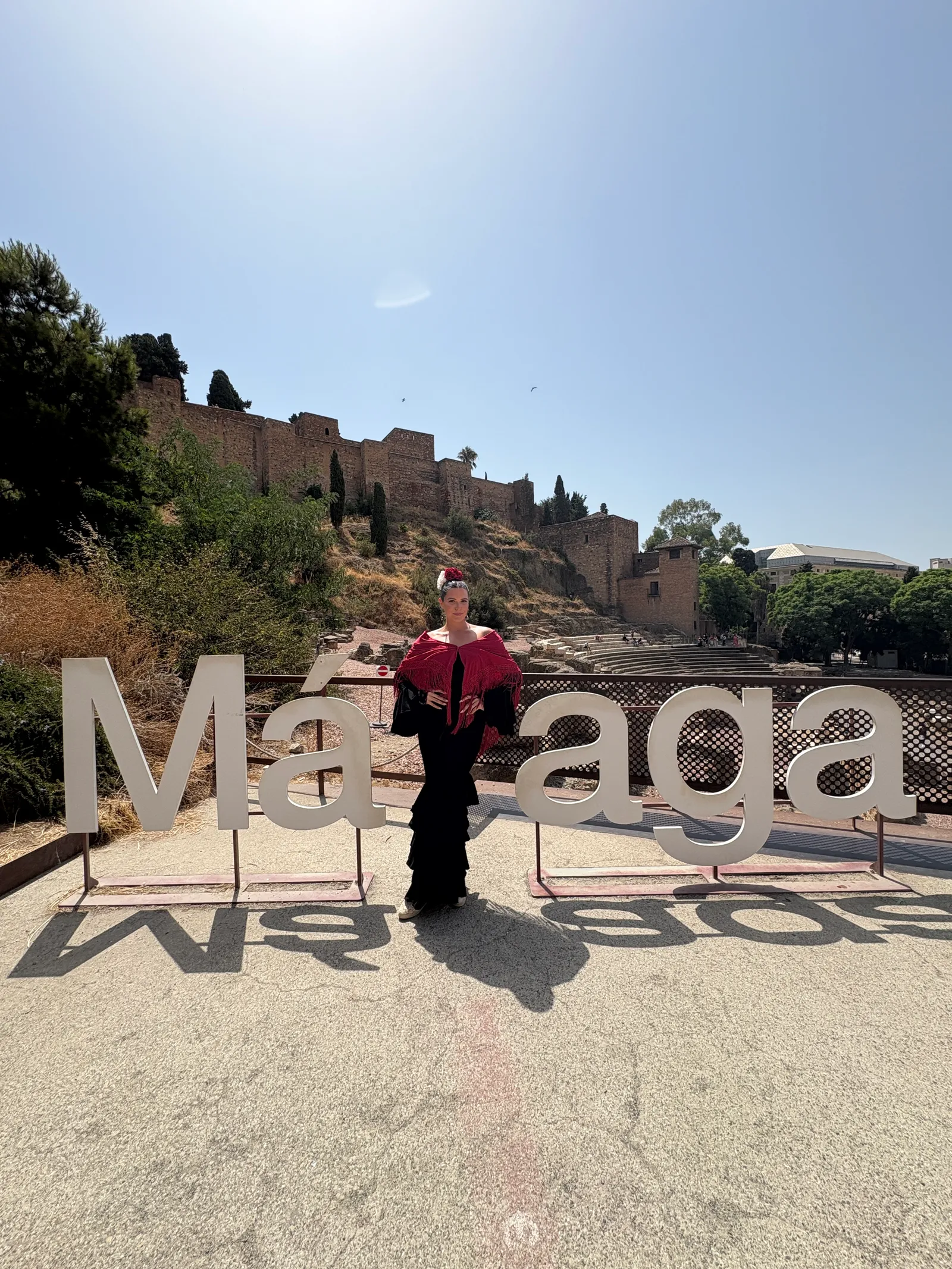 Heidi in a flamenco dress n front of the Malaga sign.
