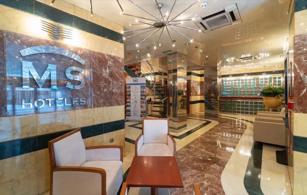 Marble lobby of Hotel MS Maestranza in Malaga, with a backlit MS Hoteles sign and spiral staircase
