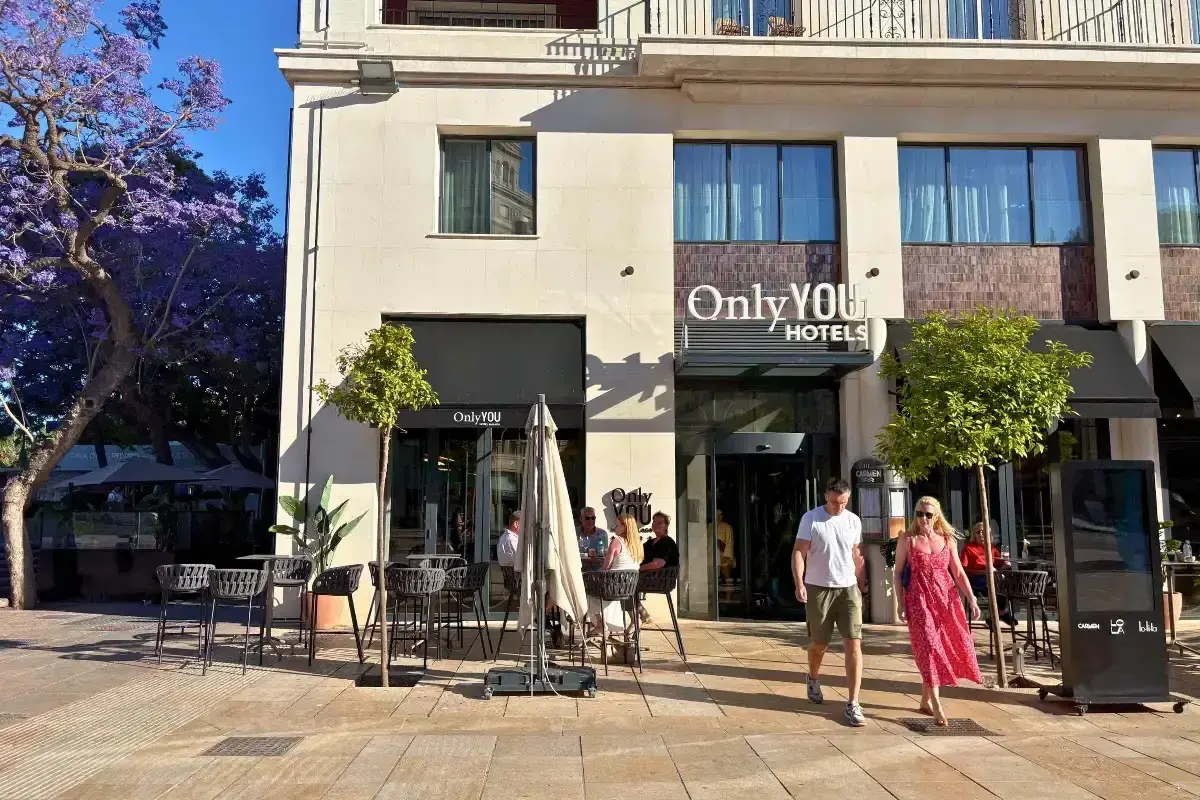 Only YOU Hotels entrance and facade on a Malaga street, with jacaranda trees and outdoor café seating
