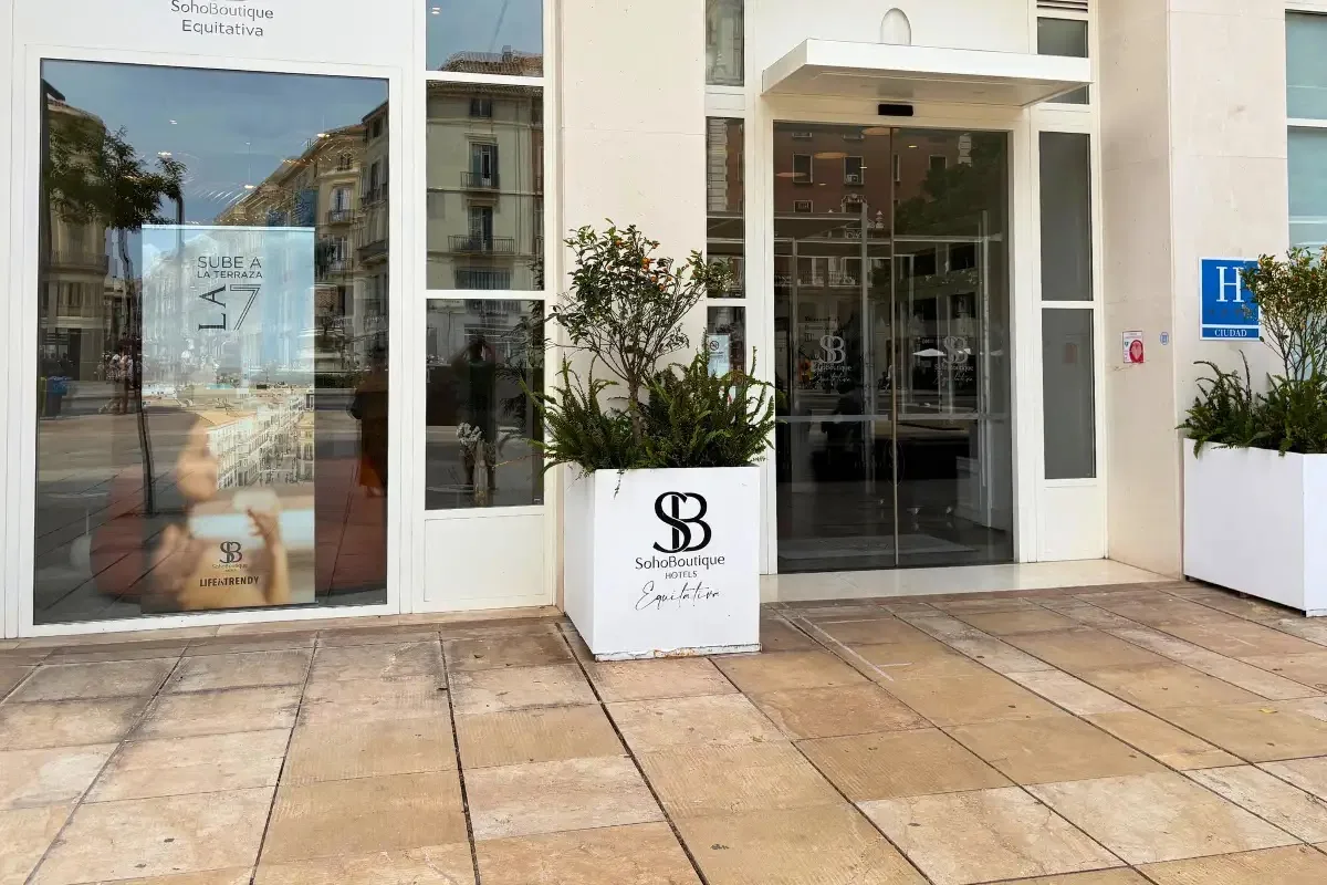 SOHO Boutique Equitativa entrance sign and glass doors on a Malaga street, with a terrace decal reading Sube a la Terraza 7