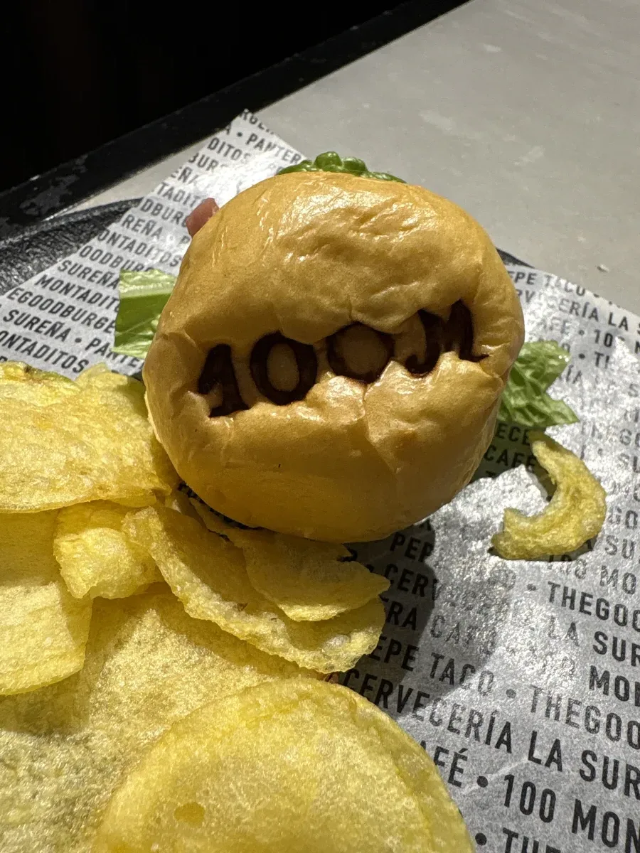 A montadito burger and crisps on branded 100 Montaditos paper in Málaga
