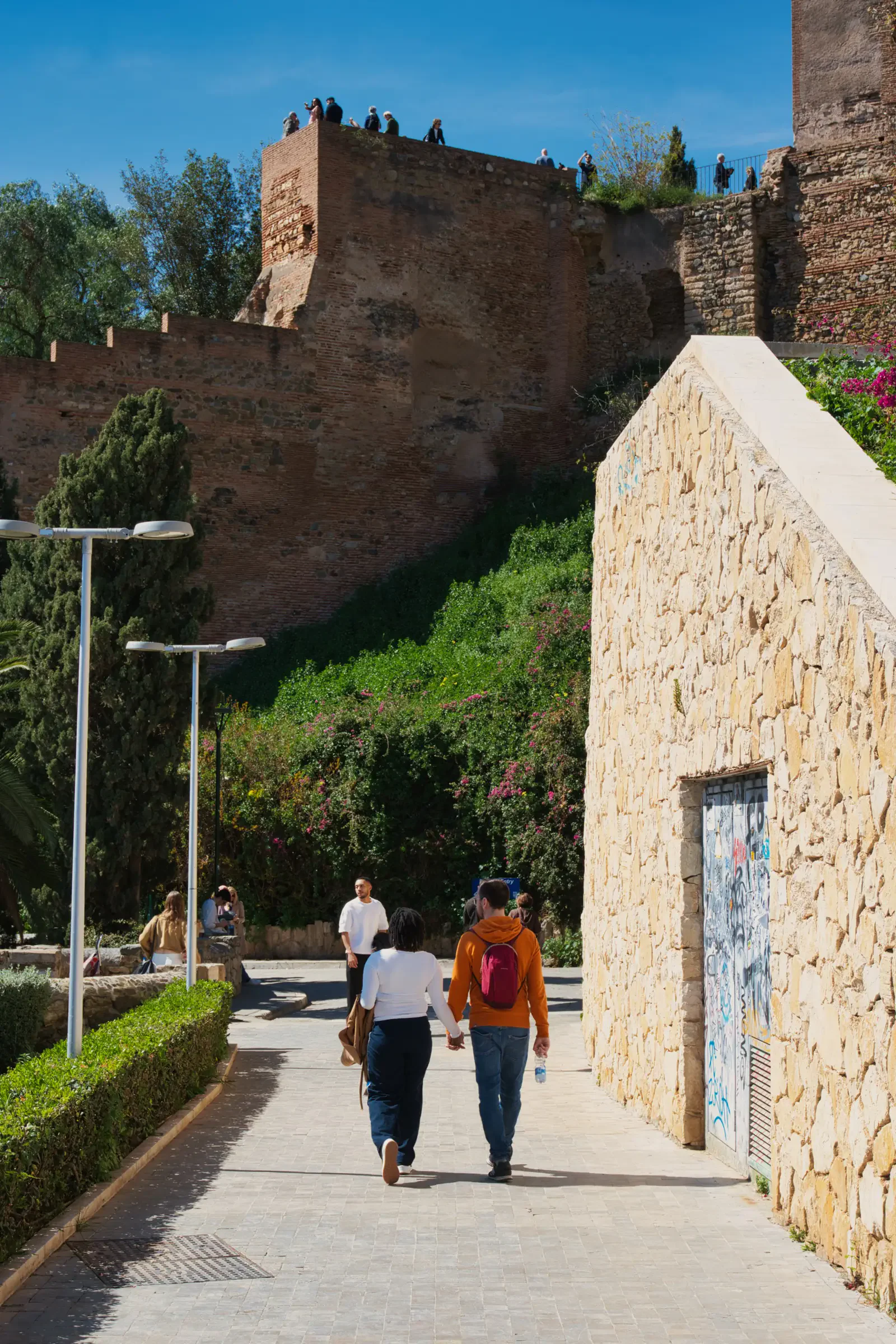 Couple walking up towards the fortress walls of the Alcazaba