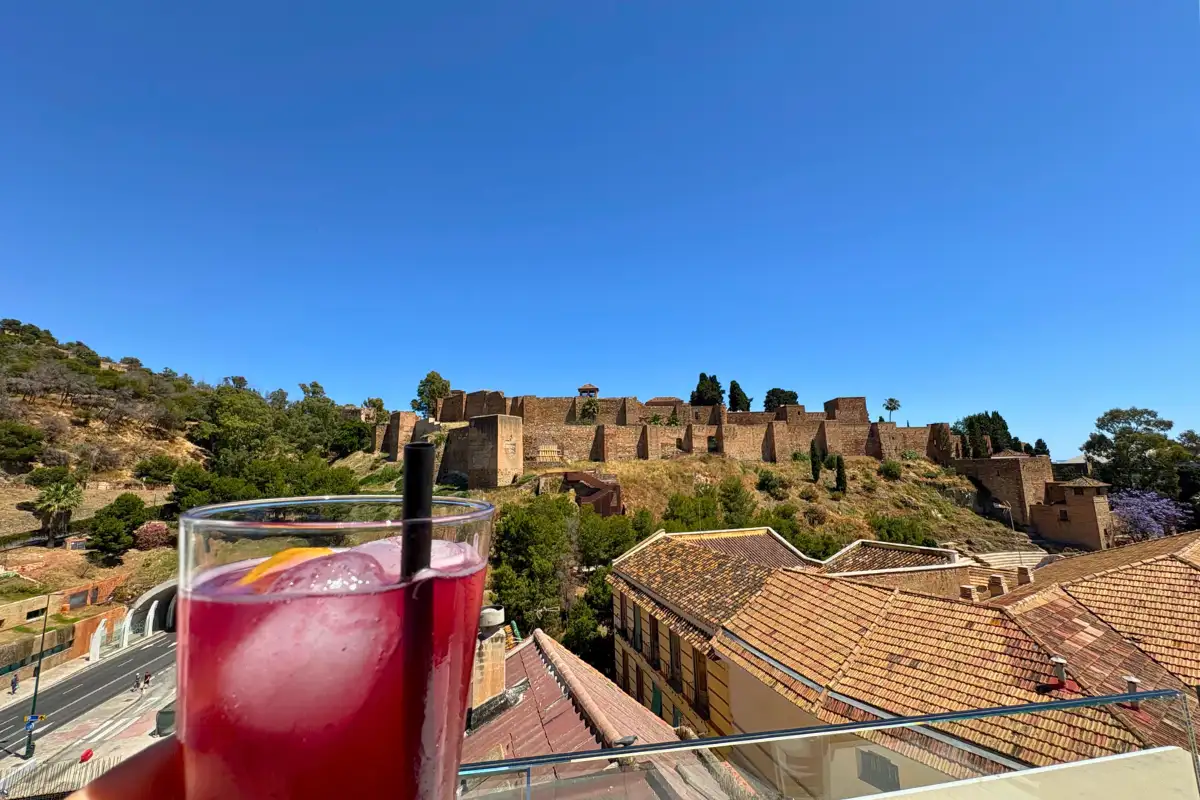 Wine glasses by the pool at Hotel Alcazaba Premium's terrace with the Málaga coastline behind
