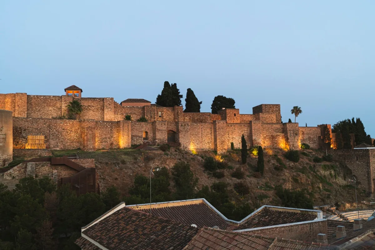 The Alcazaba's fortress walls lit up against a deep blue dusk sky