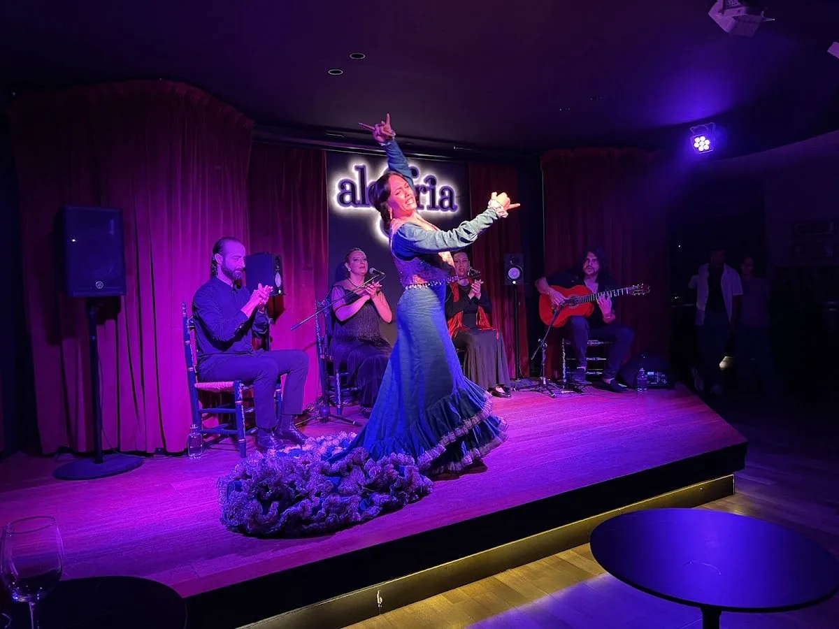 Flamenco dancer performing on stage at Alegría, with the singer, guitarist and palmas players behind her, Málaga