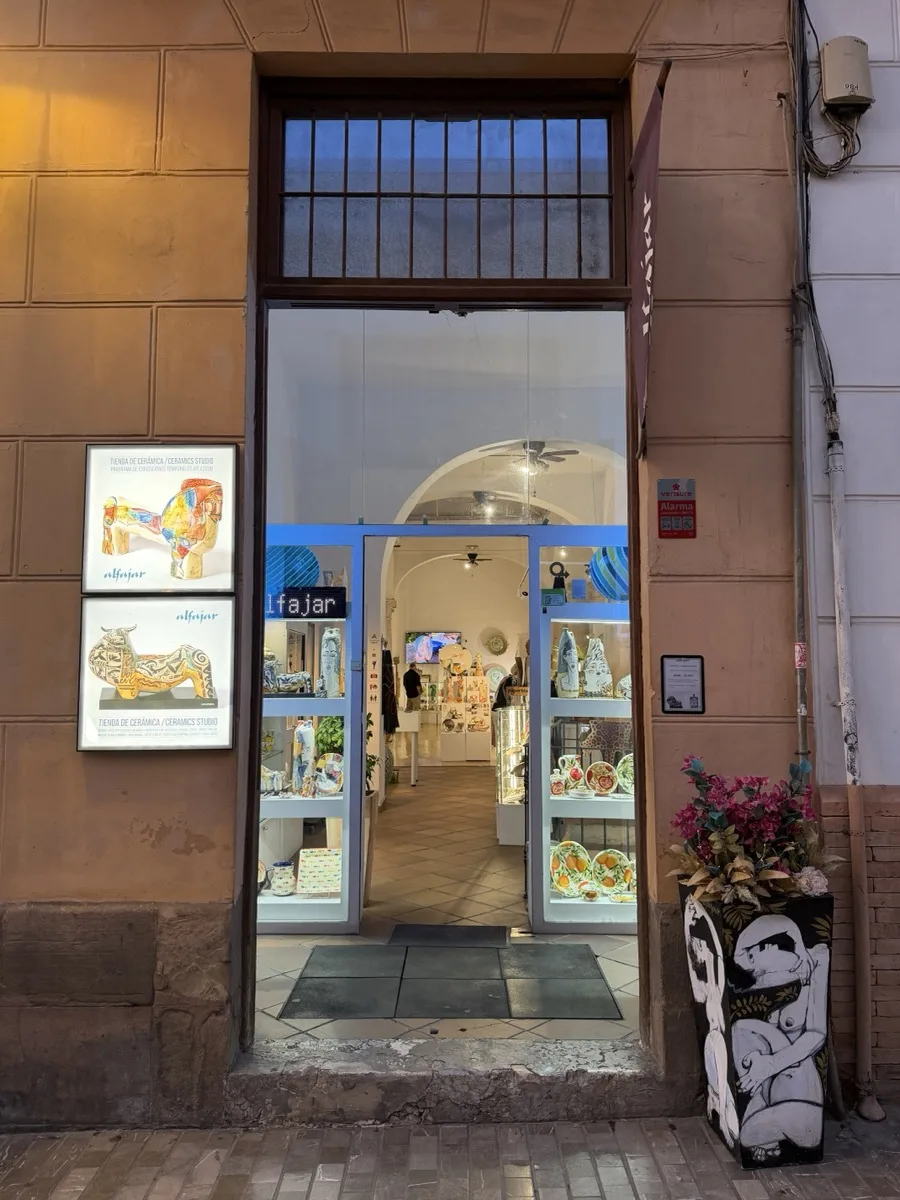 The arched, light-filled entrance to Alfajar ceramics studio in Malaga, with hand-painted ceramic animal figures displayed in the window