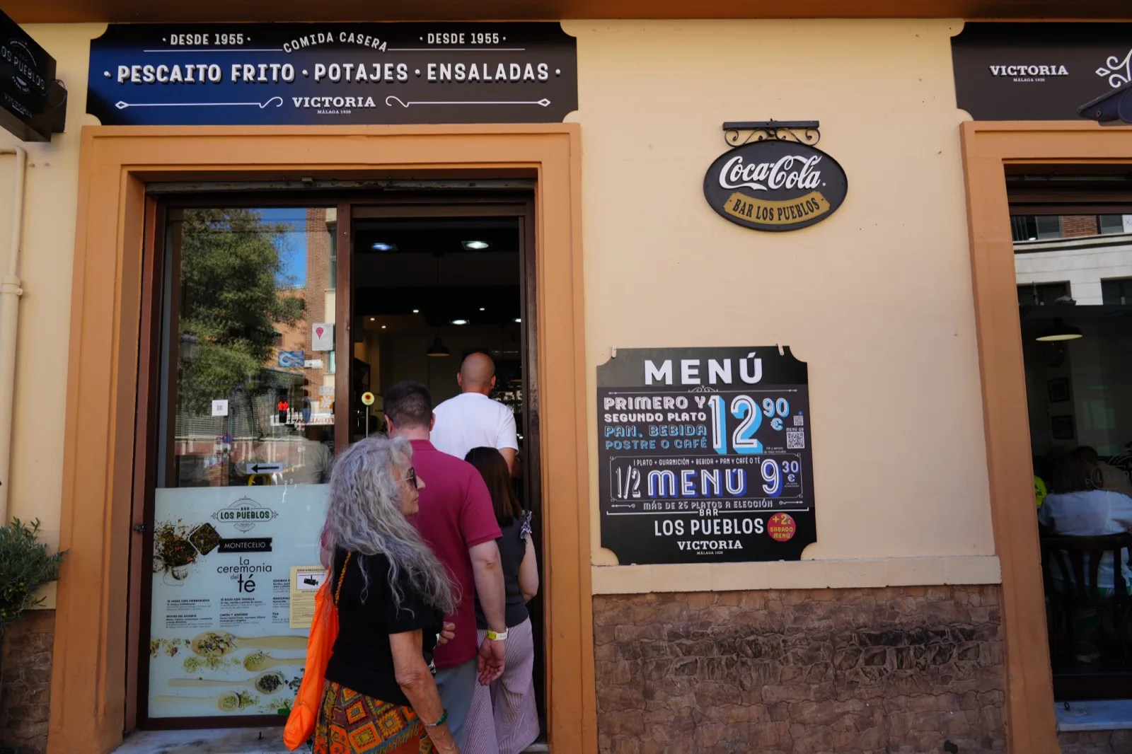 A queue outside Bar Los Pueblos in Málaga, with the menú del día board visible on the wall beside the entrance