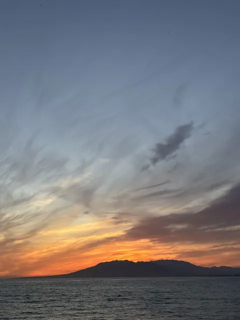 The sun gone behind the mountains across the bay at Baños del Carmen, with wispy clouds catching the last of the orange light