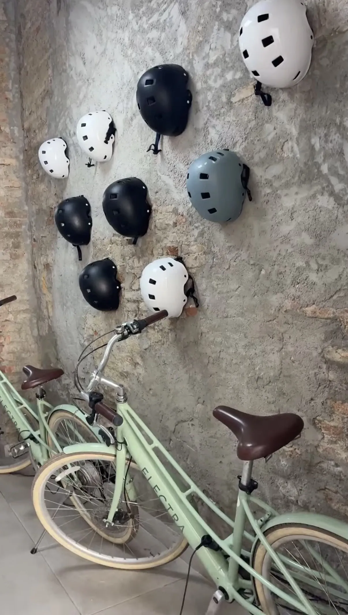 A wall of rental helmets next to vintage bikes inside the Bizi Tour shop