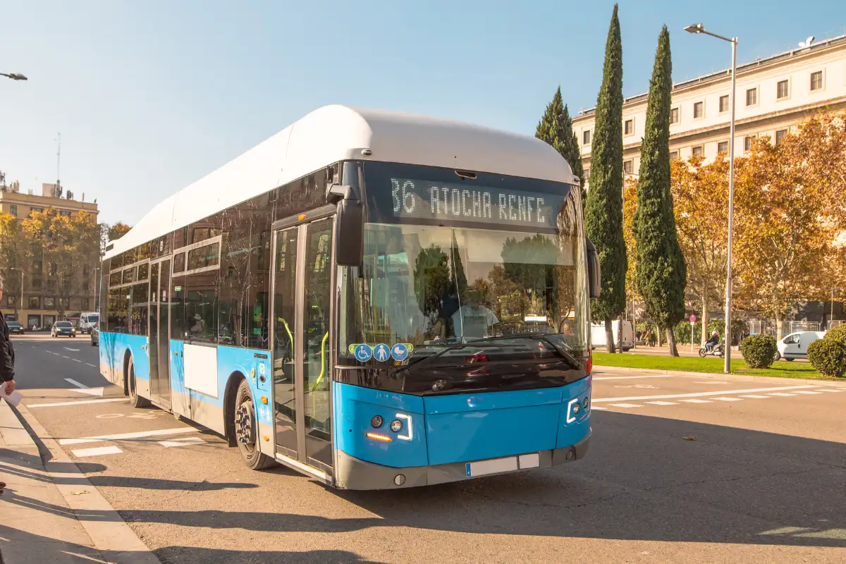 a bleu bus driving htorugh the streets of spain.