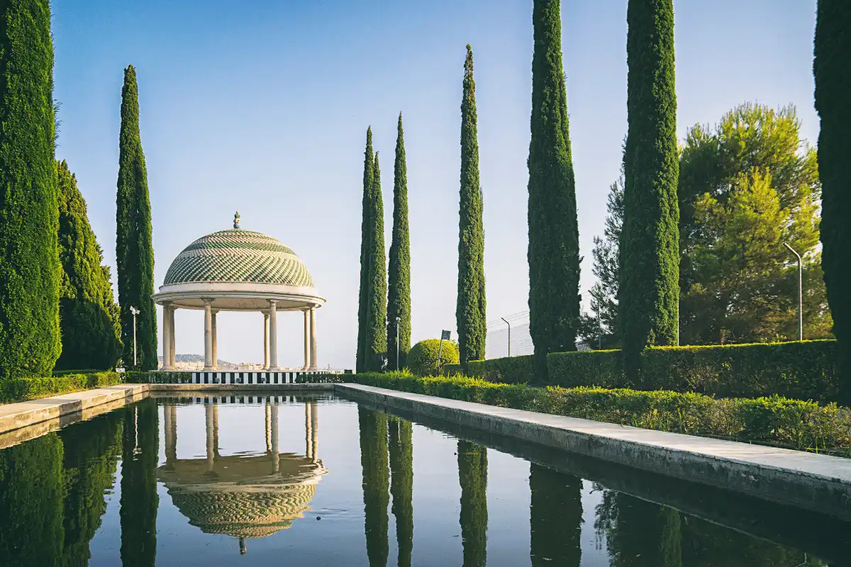 Domed pavilion reflected in the long pond between cypress trees at La Concepción botanical garden, Málaga