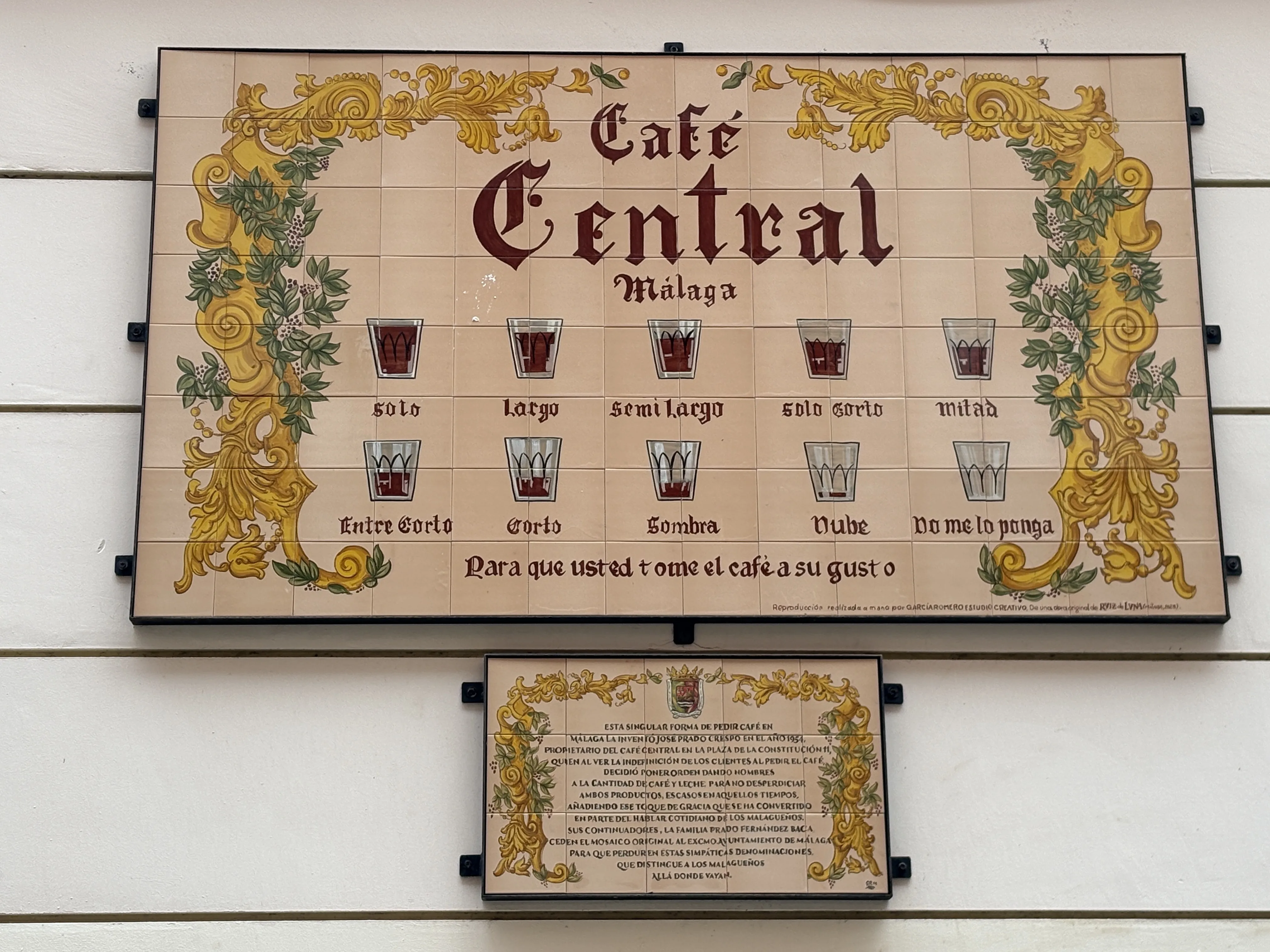 The Café Central tiled sign showing all ten Málaga coffee grades, from solo to no me lo ponga, with the explanatory plaque below