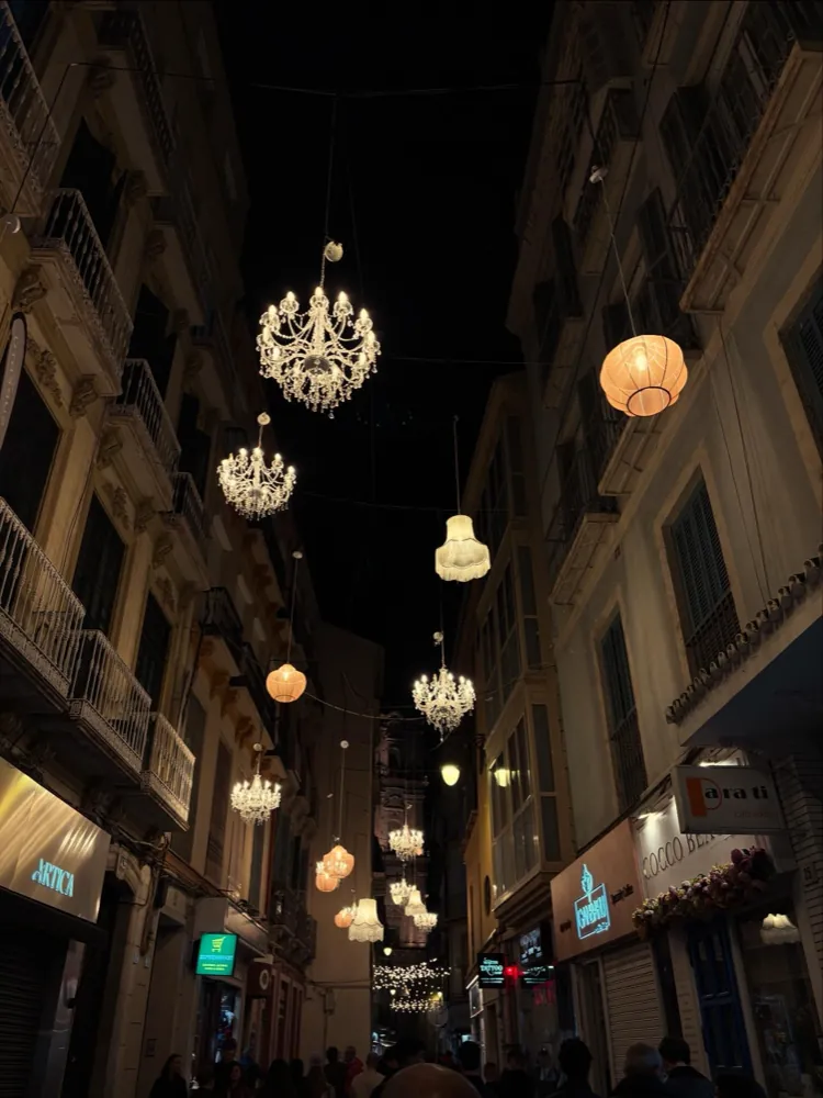 Crystal chandeliers strung above the narrow Calle San Juan at night in Malaga