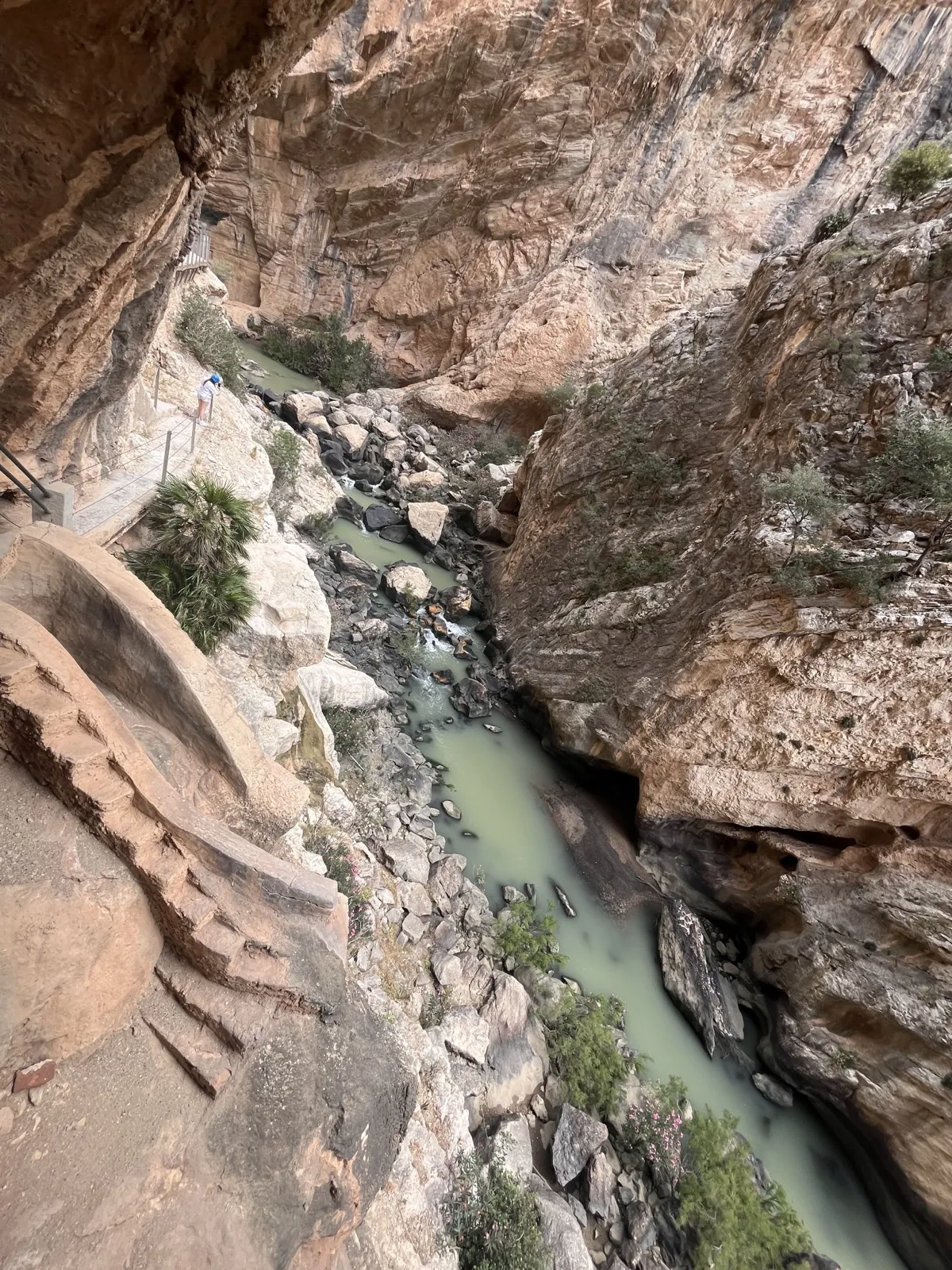 A hiker on the walkway looking down into the El Chorro gorge on the Caminito del Rey near Málaga