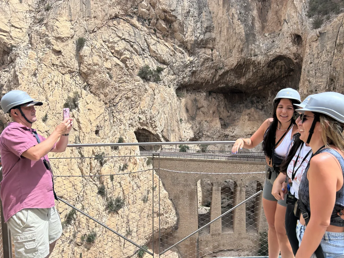 Heidi and a friend in helmets posing for a photo at a viewpoint above the old aqueduct bridge on the Caminito del Rey