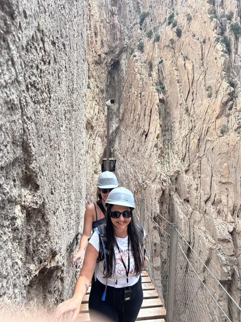 Heidi in a helmet and sunglasses on a boardwalk squeezed between the sheer walls of the Caminito del Rey gorge