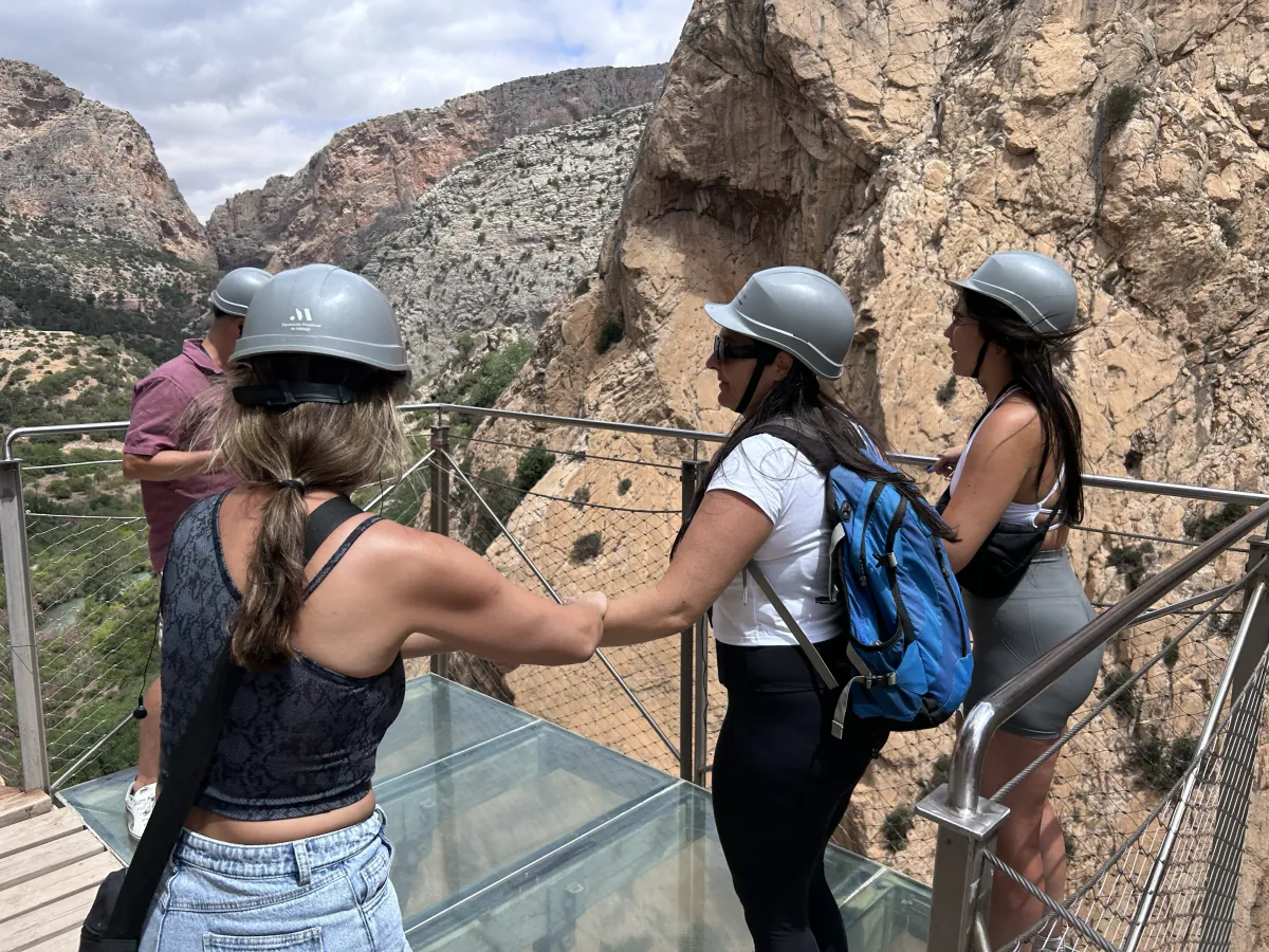 Heidi holding a friend's hand on the glass-floored balcony of the Caminito del Rey, high above the valley
