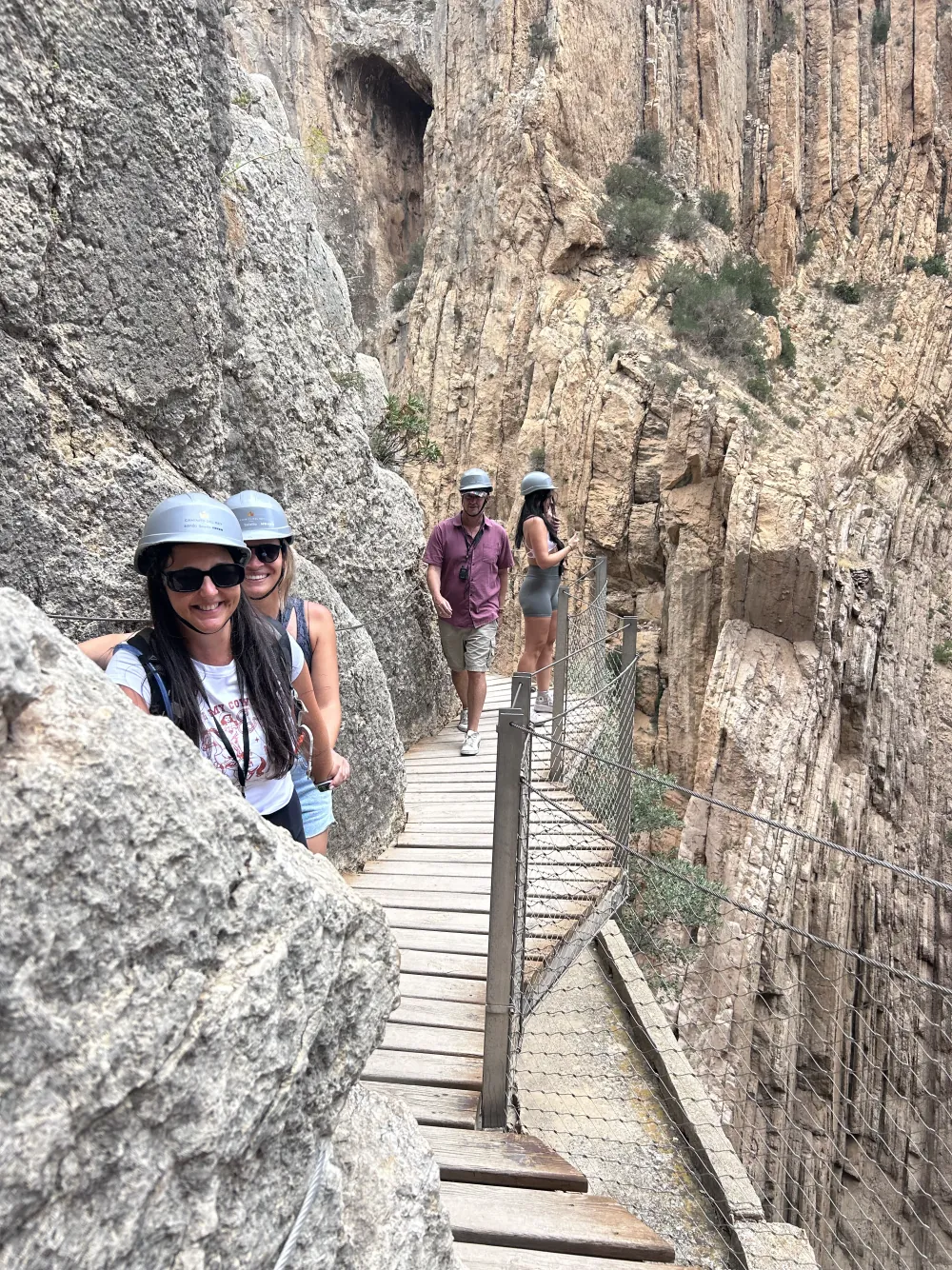 Heidi in her compulsory helmet, smiling against the rock on a Caminito del Rey boardwalk