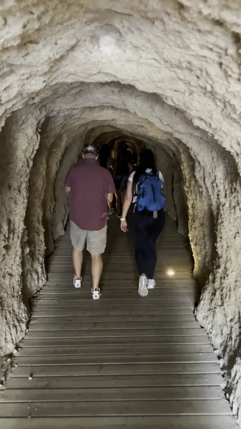 Heidi with a blue backpack walking into the narrow pedestrian tunnel on the access path to the Caminito del Rey