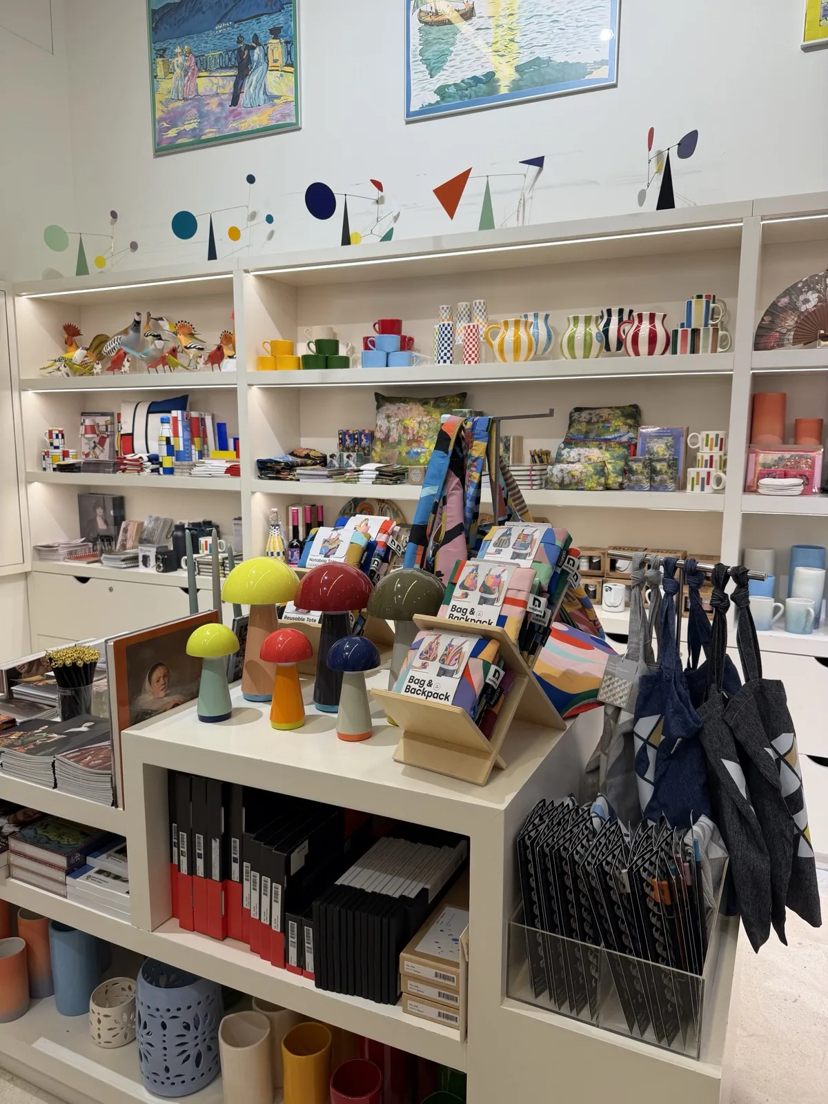 Shelves inside the Carmen Thyssen museum shop in Malaga, framed prints on the wall above ceramics, mugs, tote bags and stationery