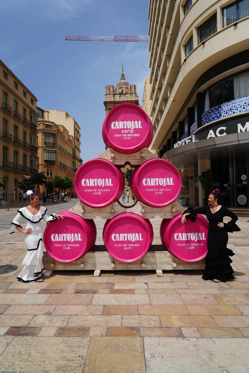 Pink Cartojal barrels stacked outside the AC Hotel for the Feria de Málaga, two women in flamenco dresses either side