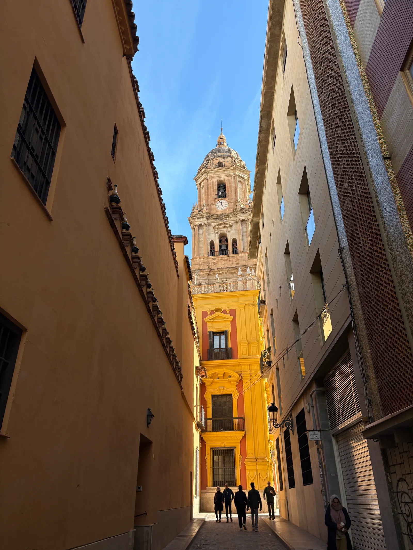 The Cathedral tower at the end of a narrow golden street in Málaga's old town