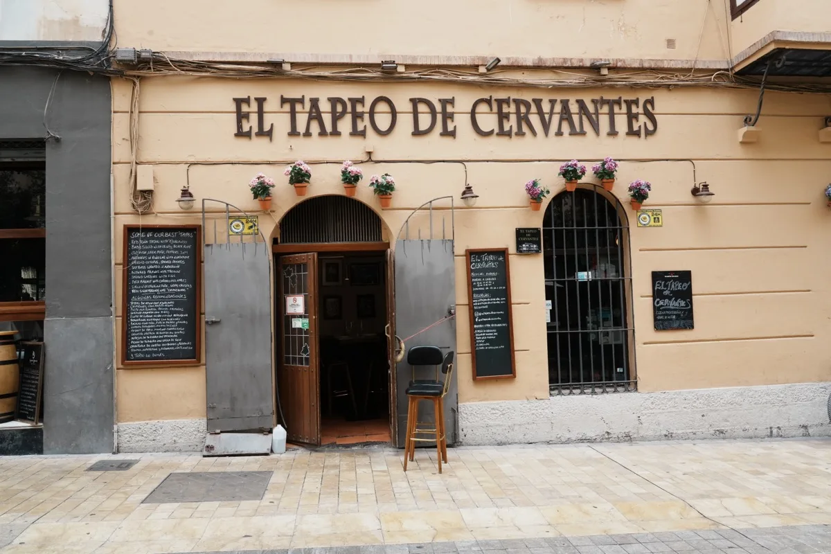 The cream frontage of El Tapeo de Cervantes on Calle Cárcer, flower pots above the door and chalkboard menus either side