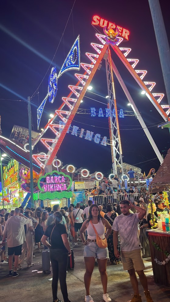 Funfair rides lit up at night at the Málaga Feria fairground