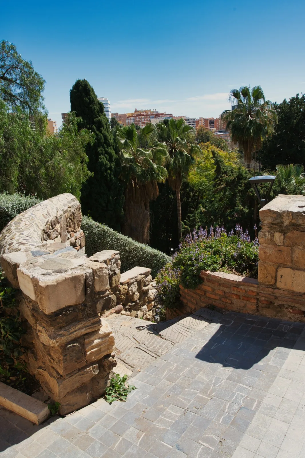 Stone terrace inside Castillo de Gibralfaro looking out over palm trees to the city