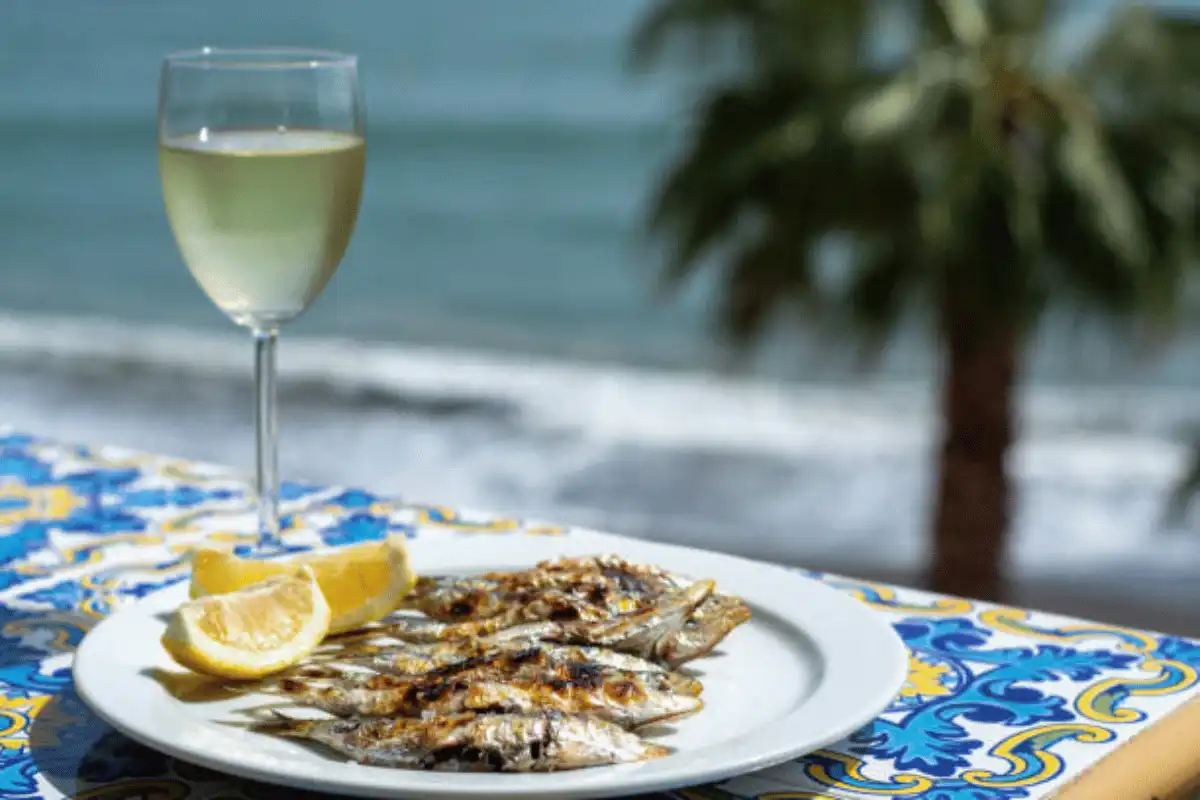 Sardines on cane skewers grilling over a wood fire on a Malaga beach