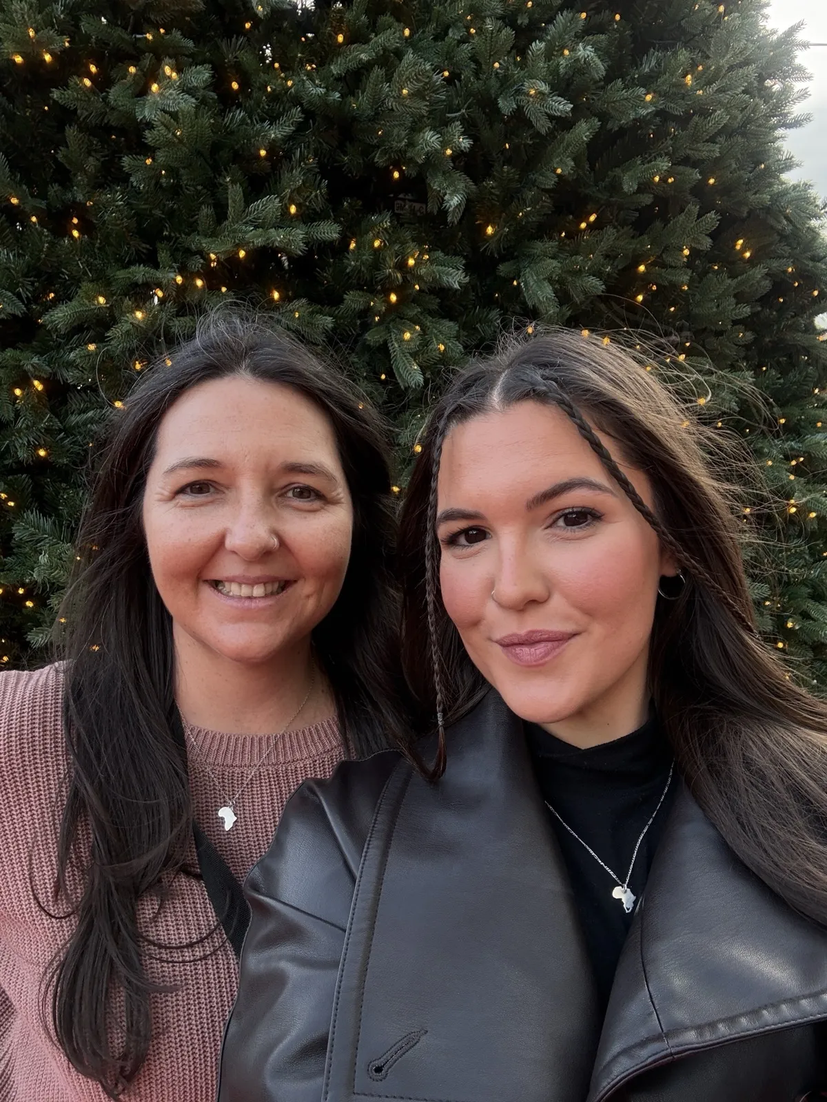Heidi smiling next to a friend in front of a lit Christmas tree in Málaga