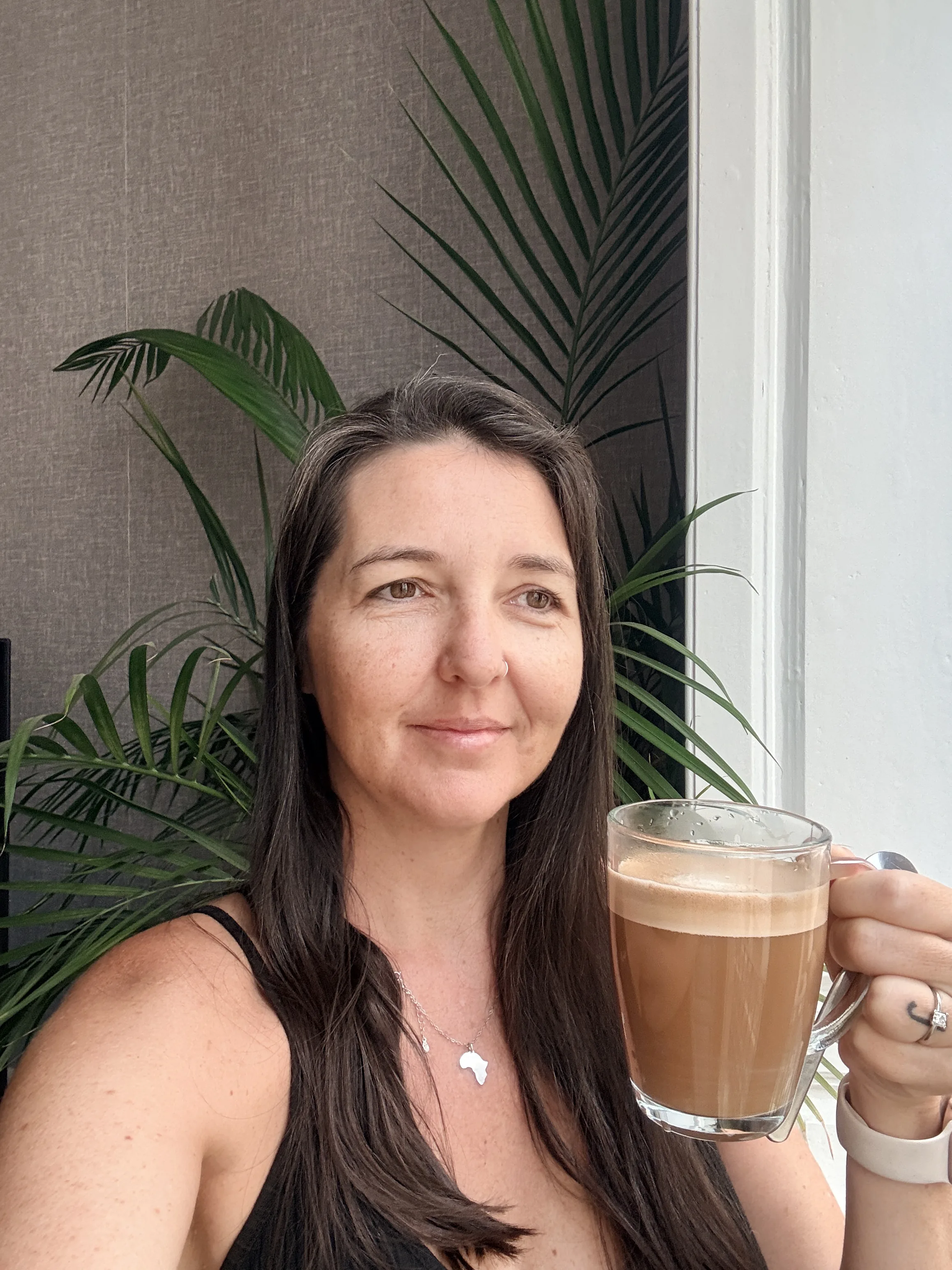 Heidi holding a glass mug of milky coffee in Málaga