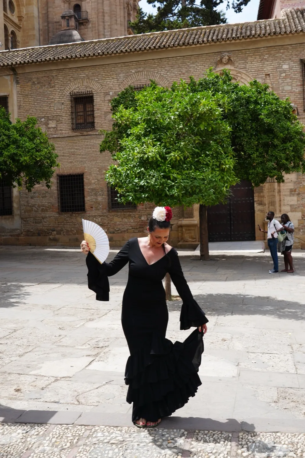 Heidi in a black flamenco dress with a fan in a courtyard near Málaga Cathedral