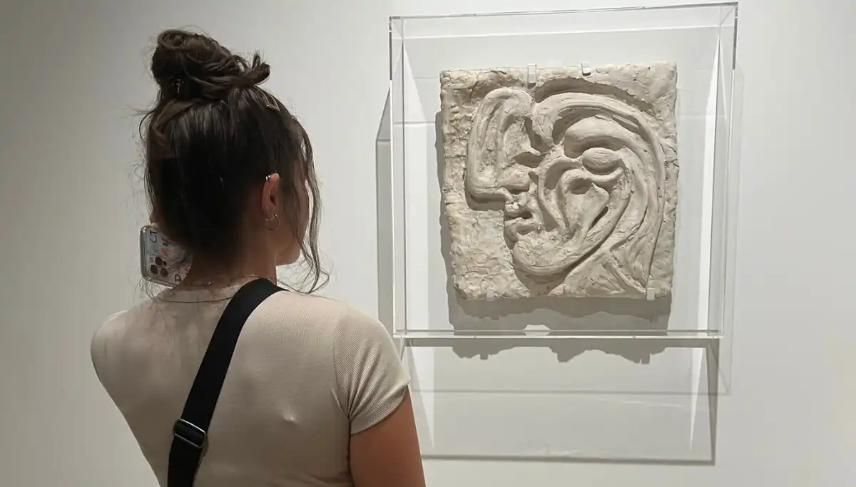 Heidi looking at a white relief sculpture in a glass case inside the Picasso Museum in Malaga