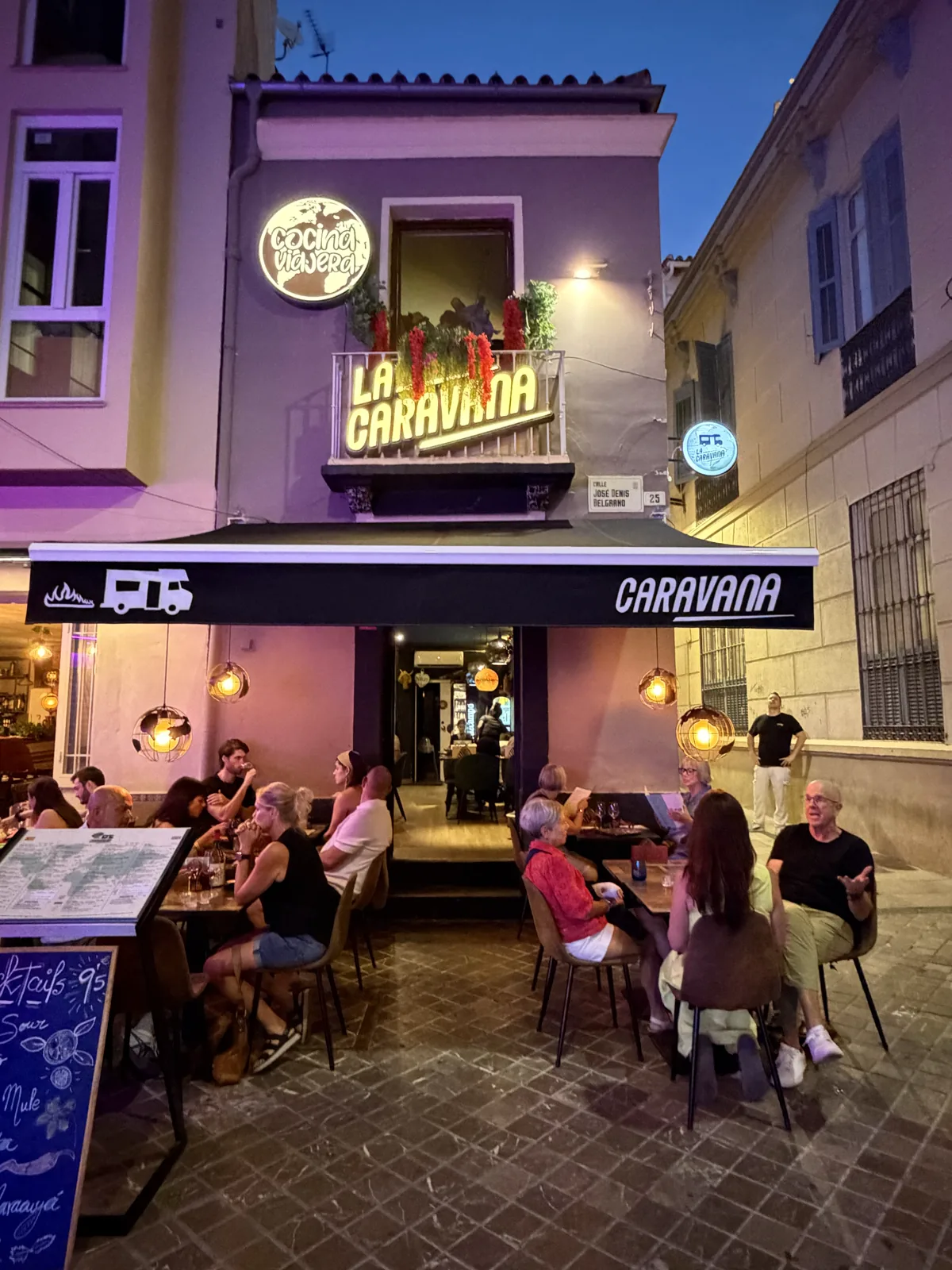 La Caravana's camper-van-themed terrace at dusk, diners at the outdoor tables under the awning, Málaga