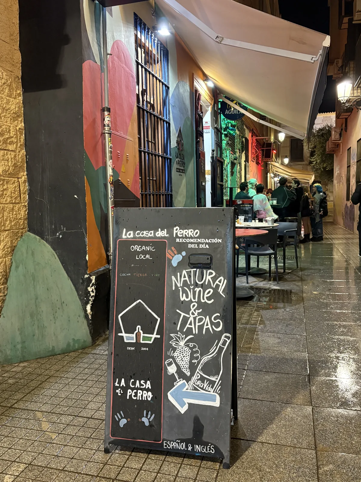 Chalkboard sandwich-board sign outside La Casa del Perro advertising natural wine and tapas, Málaga old town